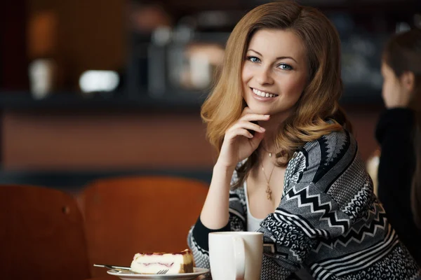 Hermosa joven sonriente mujer con una taza de café en un café —  Fotos de Stock