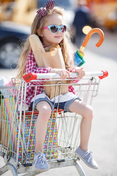 Little girl sitting in shopping trolley — Stock Photo, Image