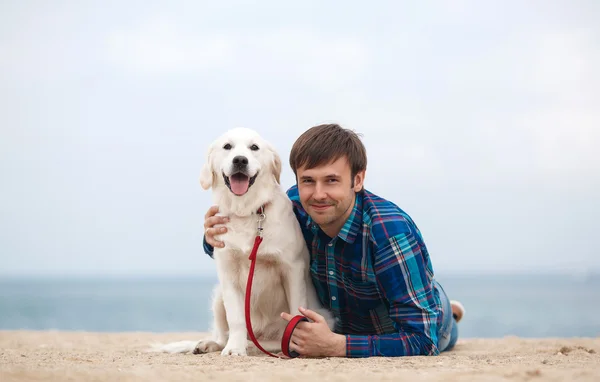 Ritratto primaverile di un giovane con un cane sulla spiaggia — Foto Stock