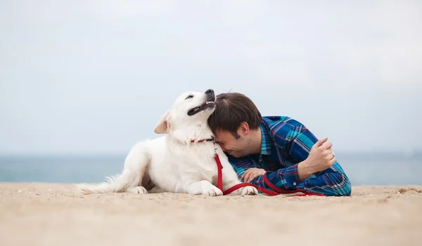 Retrato de primavera de un joven con un perro en la playa — Foto de Stock