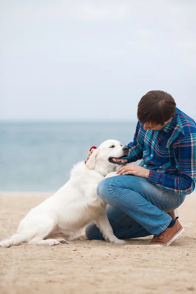 Homme et chien s'amusent au bord de la mer . — Photo