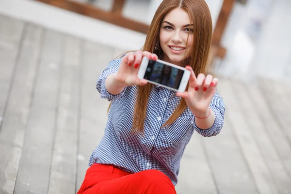 Beautiful young funky woman making selfie while sitting outdoors — Zdjęcie stockowe