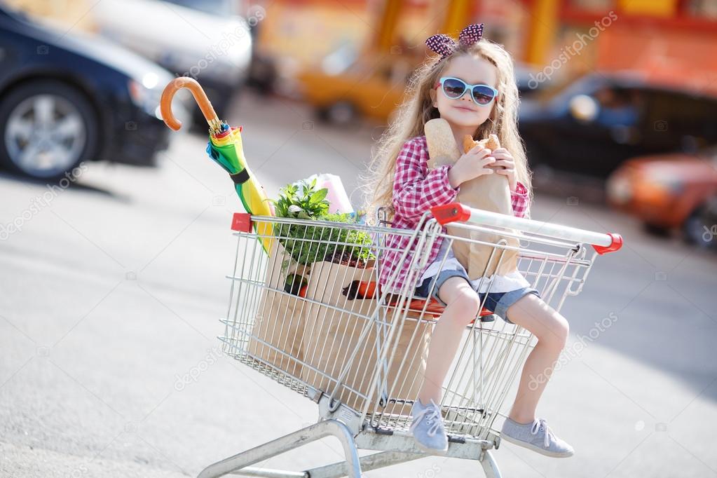 Little Girl Pushes Shopping Cart Down Sidewalk In Underwear by