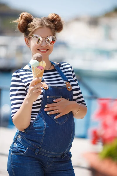 Pregnant woman with ice cream cone near the ocean