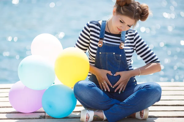 Těhotná žena s pestrým balonky na pláži — Stock fotografie