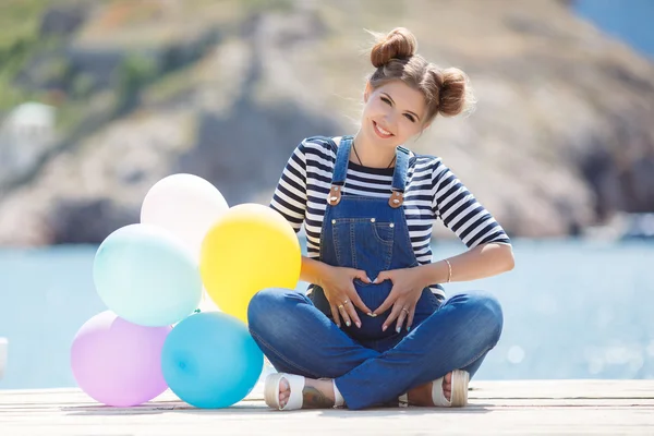 Gravid kvinna med färgglada ballonger på stranden — Stockfoto