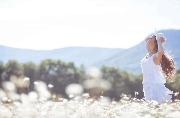 Portrait of a young woman wearing a hat in a field of blooming daisies — Stock Photo, Image