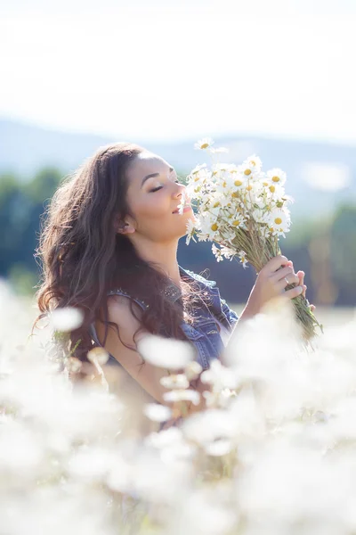 Una joven con un ramo de margaritas blancas en un prado — Foto de Stock