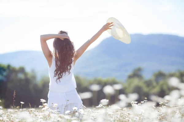 Retrato de una joven con sombrero en un campo de margaritas florecientes — Foto de Stock