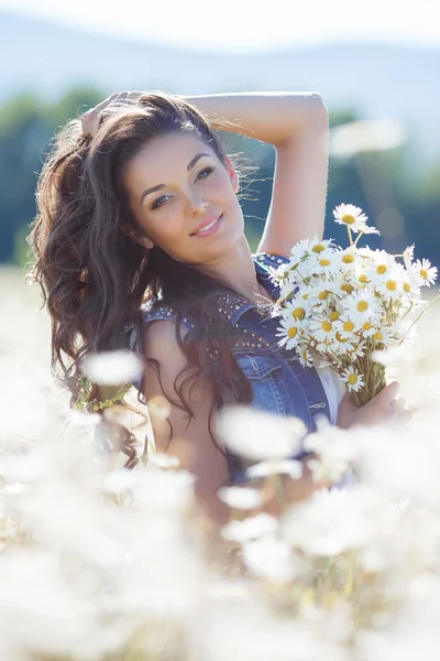 Una joven con un ramo de margaritas blancas en un prado —  Fotos de Stock