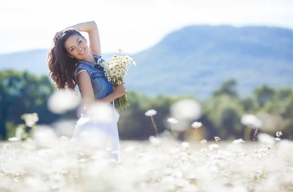 Una joven con un ramo de margaritas blancas en un prado — Foto de Stock