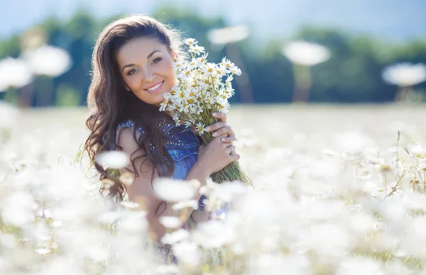 Mladá žena s kyticí bílými sedmikrášemi na louce — Stock fotografie