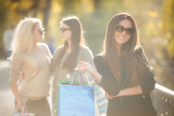 Femme heureuse avec des achats sur un fond d'amis — Photo