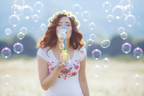 Portrait of beautiful pregnant woman in field blowing bubbles — Stock Photo, Image