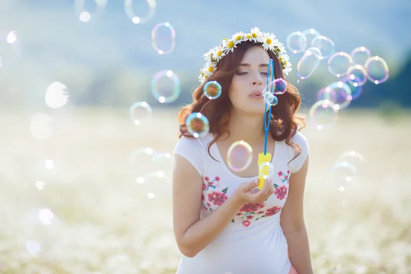 Retrato de una hermosa mujer embarazada en el campo soplando burbujas —  Fotos de Stock