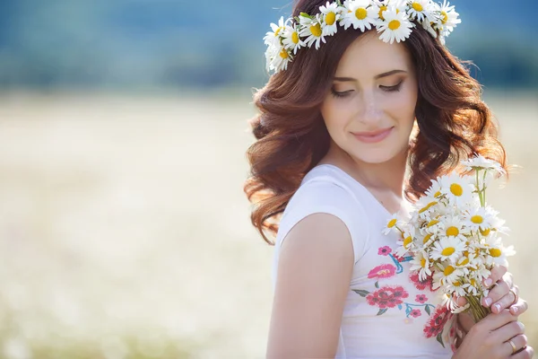 Uma mulher grávida em um campo com um buquê de margaridas brancas — Fotografia de Stock