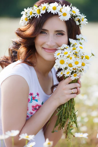 Una mujer embarazada en un campo con un ramo de margaritas blancas —  Fotos de Stock
