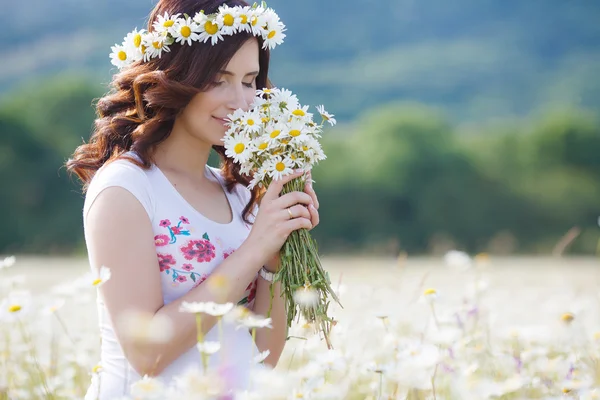 Uma mulher grávida em um campo com um buquê de margaridas brancas — Fotografia de Stock