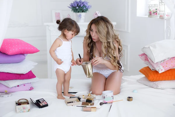 Mãe e filha fazendo maquiagem sentadas na cama no quarto — Fotografia de Stock