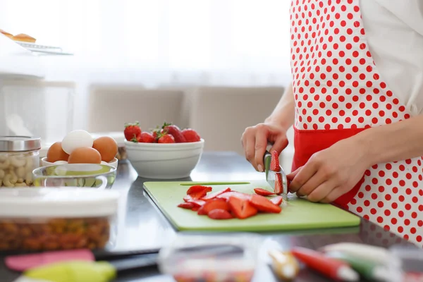 Frau schneidet Erdbeeren auf Küchentisch. — Stockfoto