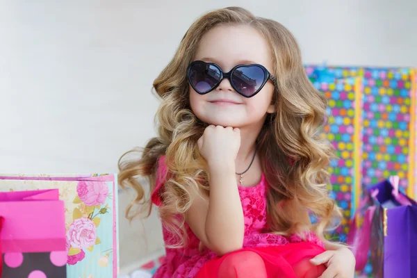 Linda niña con bolsas de colores para ir de compras en el supermercado —  Fotos de Stock