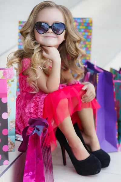 Linda niña con bolsas de colores para ir de compras en el supermercado —  Fotos de Stock