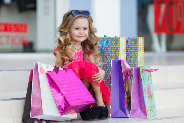 Το χαριτωμένο μικρό κορίτσι με πολύχρωμες τσάντες για ψώνια στο σούπερ μάρκετ — Φωτογραφία Αρχείου