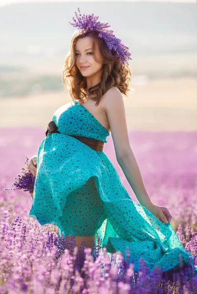 Беременная женщина в бирюзовом платье на лавандовом поле — стоковое фото