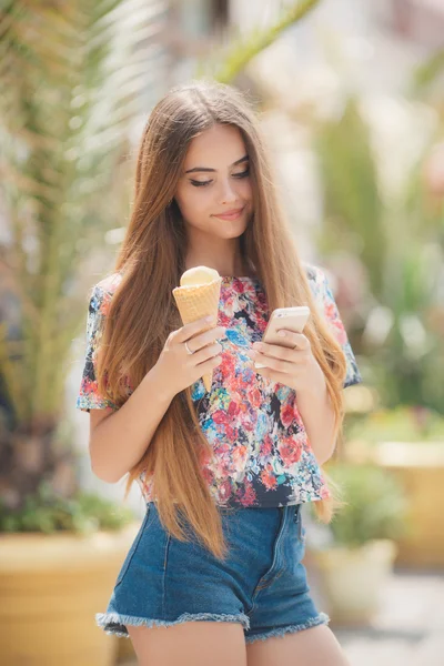 Hermosa chica con helado lee el mensaje en el teléfono móvil — Foto de Stock