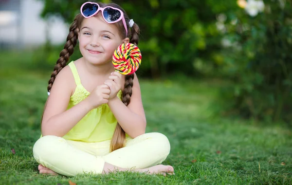 Schattig klein meisje met grote kleurrijke Lollipop. — Stockfoto