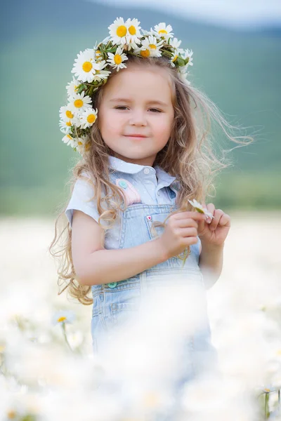 Klein meisje in een krans van witte madeliefjes — Stockfoto