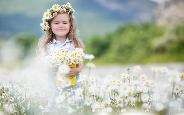 Schattig klein meisje met gele emmer wit madeliefjes — Stockfoto