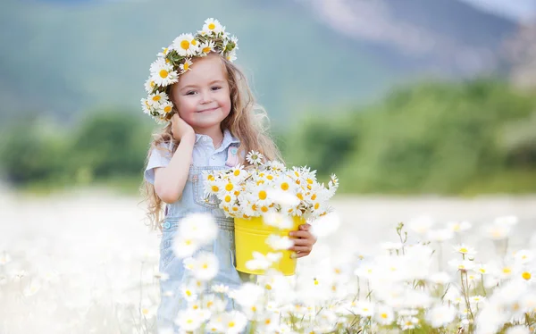 Linda niña con cubo amarillo margaritas blancas — Foto de Stock