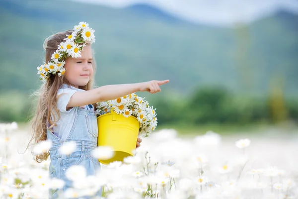 Schattig klein meisje met gele emmer wit madeliefjes — Stockfoto