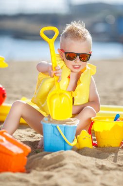 Küçük bir çocuk kumsalda oynuyor.