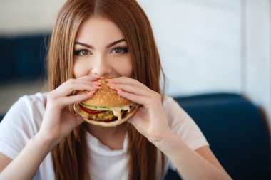 Bir kafede bir masa için hamburger ile Bayan