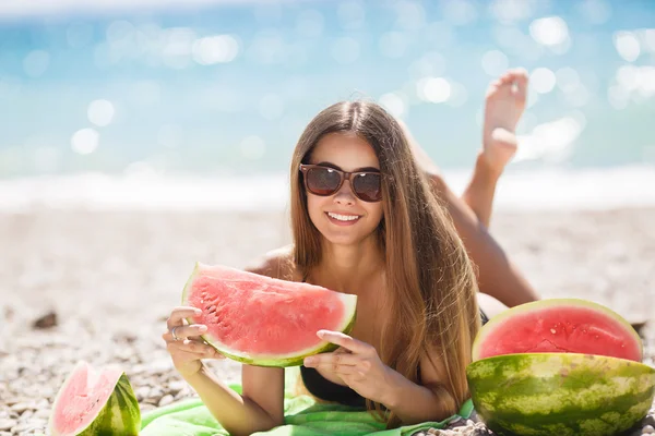 Mooi meisje op strand eten van watermeloen — Stockfoto