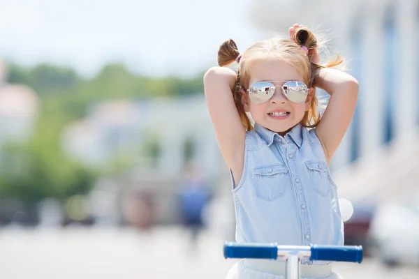 Little girl riding a scooter in the city — Stock Photo, Image