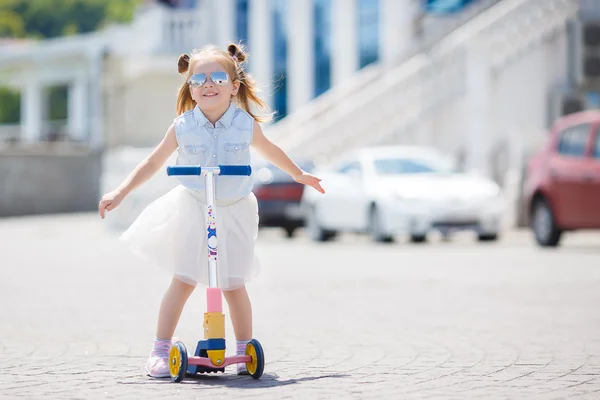 Küçük kız şehirde scooter kullanıyor. — Stok fotoğraf