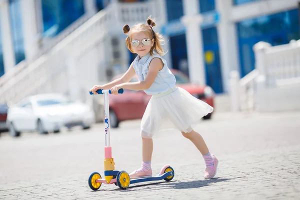Little girl riding a scooter in the city — Stock Photo, Image