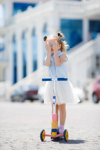 Little girl riding a scooter in the city — Stock Photo, Image