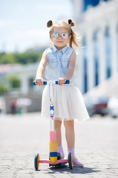 Little girl riding a scooter in the city — Stock Photo, Image