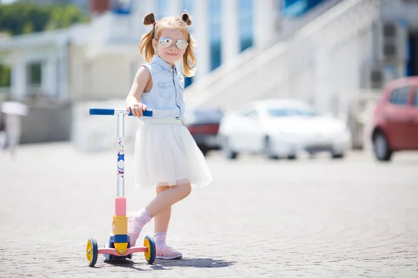 Little girl riding a scooter in the city — Stock Photo, Image