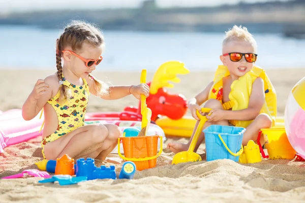 Little brother and sister playing on the beach in the sand — Stock Photo, Image