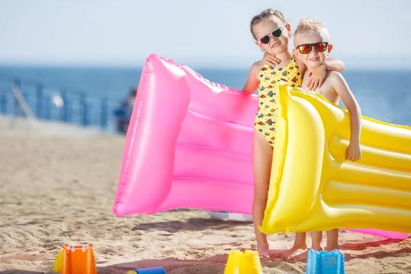 Ragazza e ragazzo sulla spiaggia con materasso gonfiabile — Foto Stock