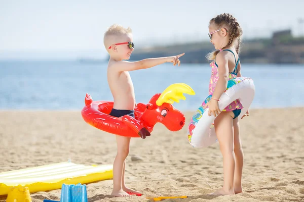 Crianças engraçadas com bóias coloridas na praia — Fotografia de Stock