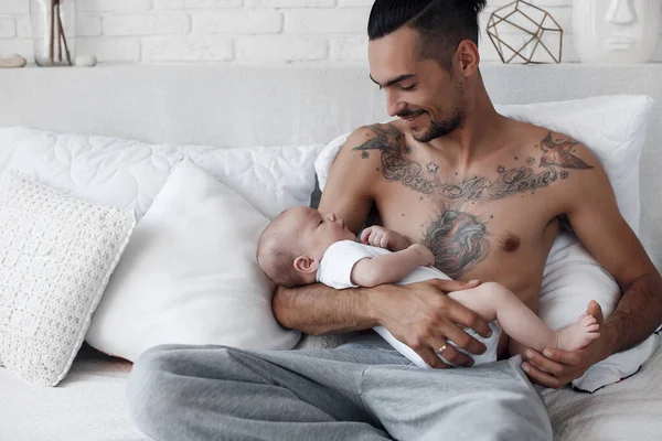 Uomo con neonato. famiglia felice a casa. felice padre con carino due mesi bambino sdraiato nel letto leggero a casa — Foto Stock
