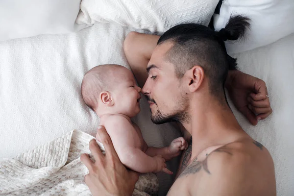 Homem com criança. família feliz em casa. pai feliz com bonito dois meses bebê menino deitado na cama leve em casa — Fotografia de Stock