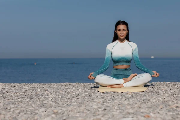 Kavkazská mladá žena cvičí jógu na pobřeží — Stock fotografie