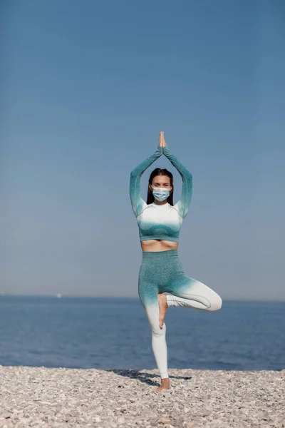 Młoda kobieta w masce ćwiczenia jogi na świeżym powietrzu — Zdjęcie stockowe